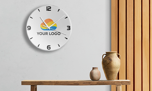 Round wall clock with YOUR LOGO colorful design at center, time around 10:10, wooden table with ceramic vases below