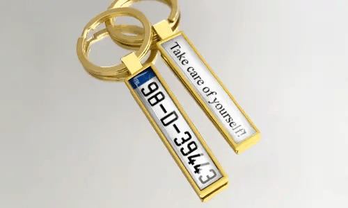 Llavero de metal dorado con diseño personalizado de placa de matrícula y texto grabado