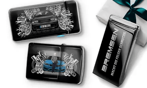 Three automotive-themed items featuring car illustrations and machinery motifs, arranged with a gift box tied with a green ribbon on the side.