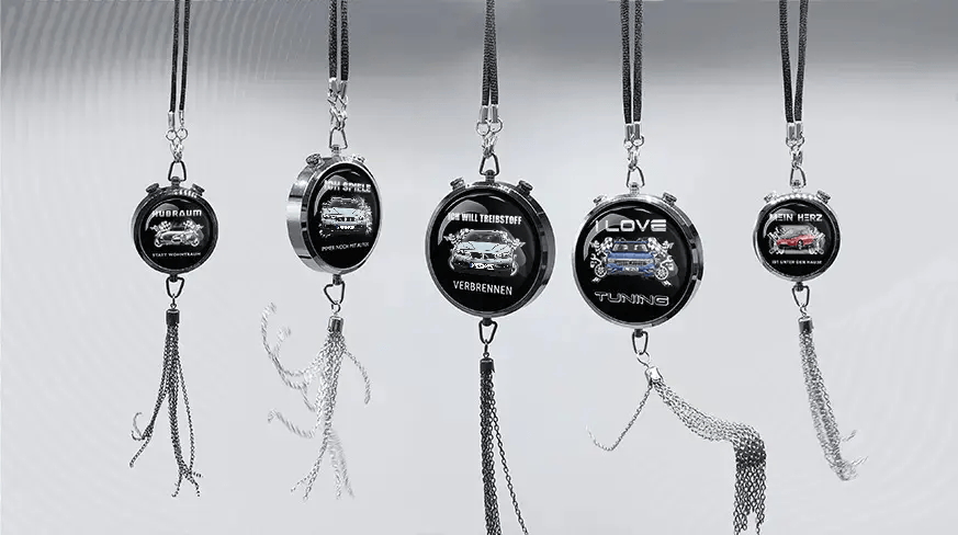 Five round keychains with German car-themed slogans and illustrations, hanging in a row
